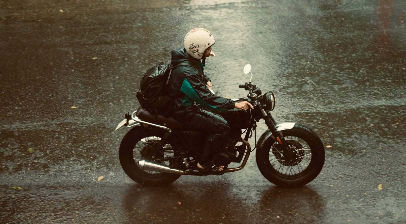 a man riding a motorcycle down a rain soaked street